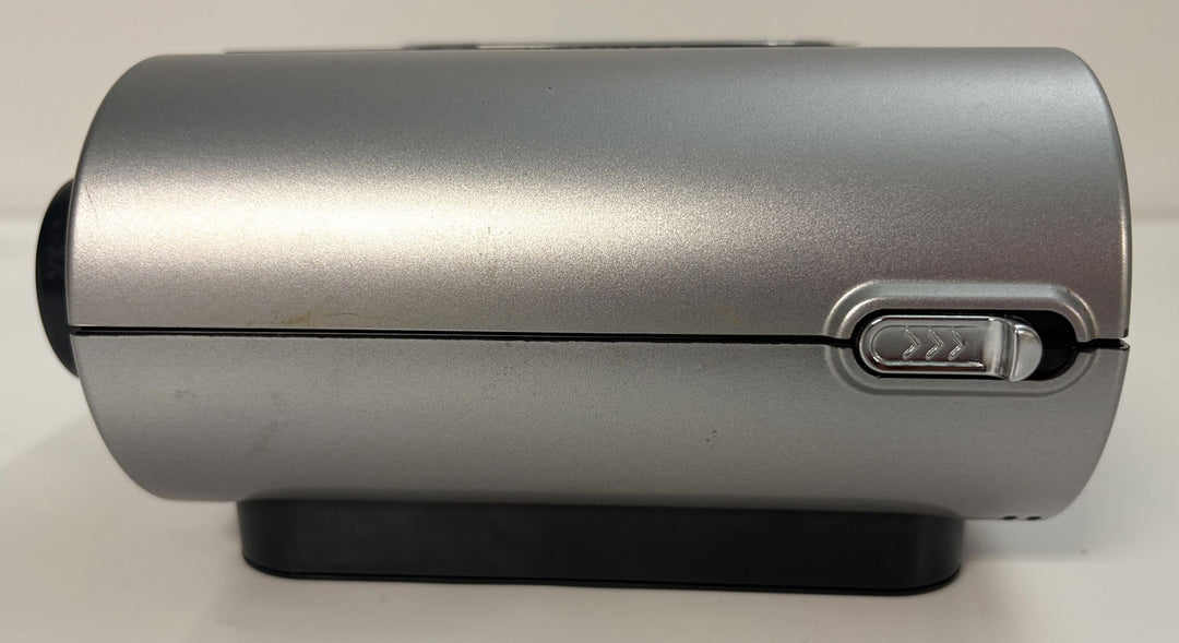 Compact silver cylindrical humidifier component with a sliding release button on the side, designed for use with Resmed CPAP devices, shown resting on a black base.