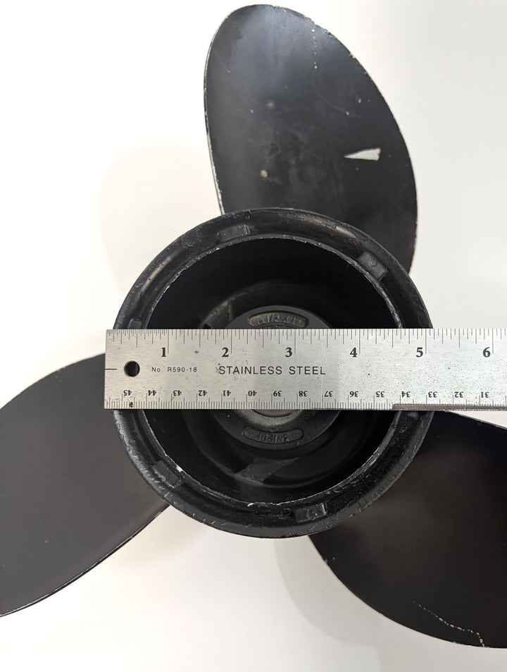 Top view of a pre-owned black Volvo aluminum propeller with three blades, featuring a stainless steel ruler measuring the 19-spline drive hub diameter.