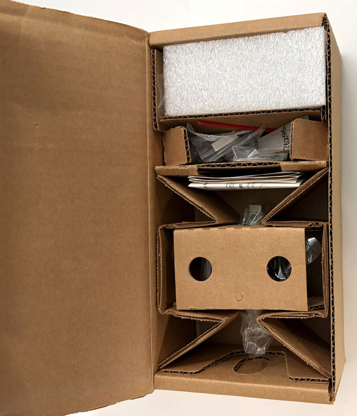 Open brown cardboard box with protective inserts containing a Baldwin privacy door lever and installation hardware wrapped in plastic and cushioned with foam pieces