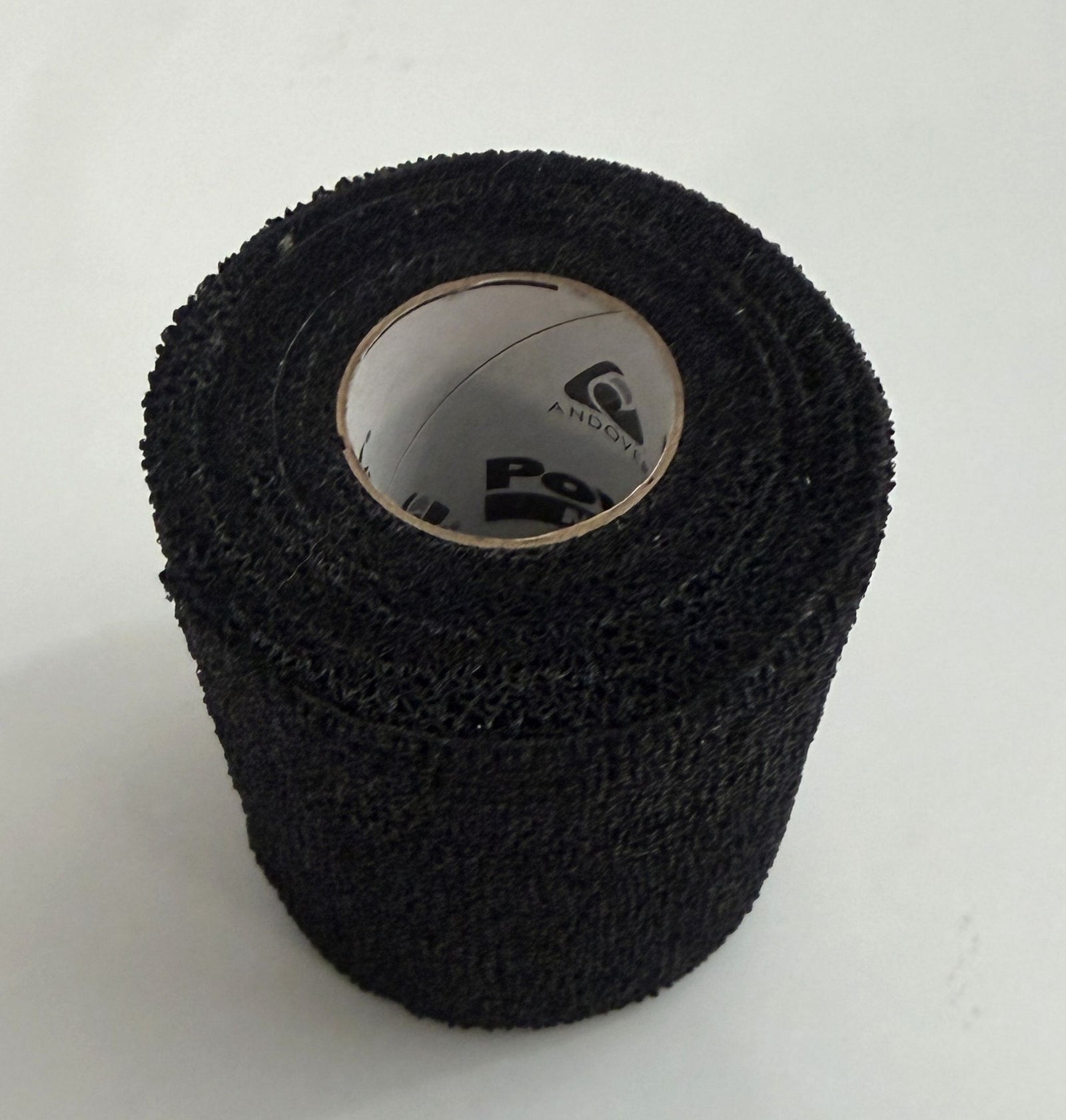 Close-up of a single black roll of PowerFlex sports wrap featuring textured self-adhering material, suitable for athletic support and compression by Milliken.