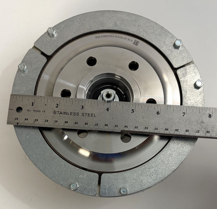 Top-down view of a BorgWarner Kysor K32 rear air fan clutch with metal housing, multiple bolts, and a stainless steel ruler measuring its diameter on a white surface.