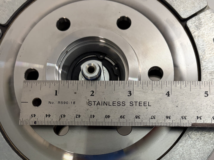 Close-up of a BorgWarner Kysor K32 rear air fan clutch showing stainless steel metal surface with mounting holes and a ruler measuring the diameter for size reference.