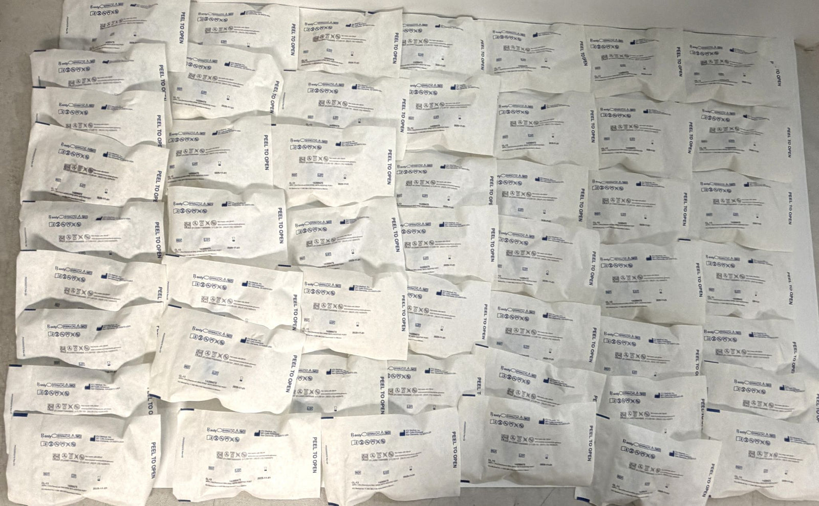 Multiple individually packaged ICU Medical ChemoLock CL-13 bag spikes with additive port, arranged in rows on a flat surface, new and sterile medical supplies for clinical use.