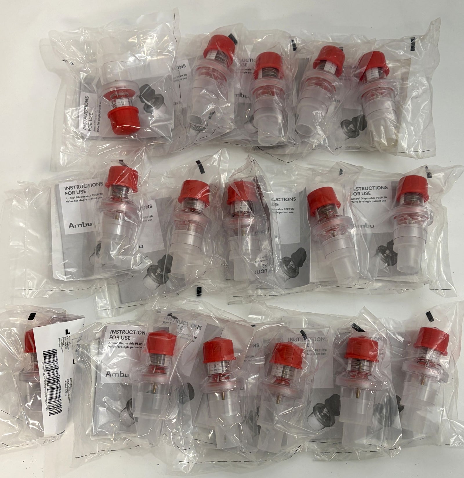 Multiple individually packaged Ambu medical respiratory devices with clear plastic bodies and red caps, arranged on a white surface