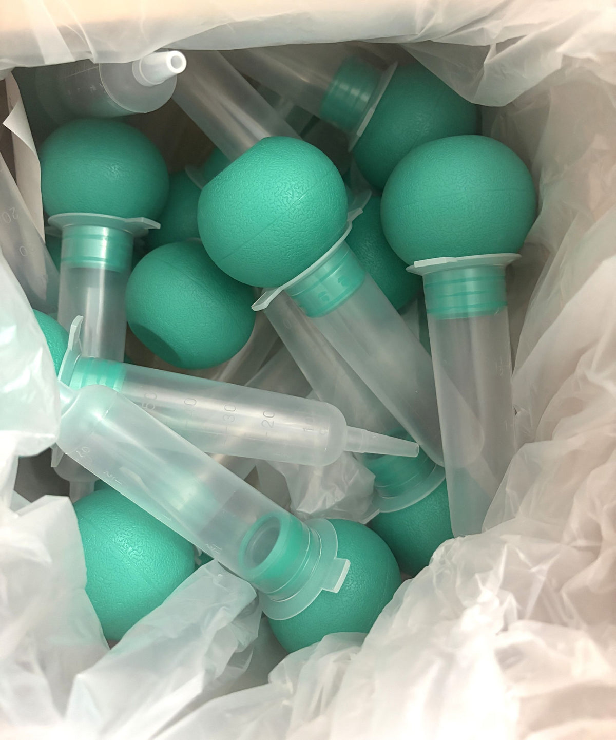 Amsino teal bulb irrigation syringes with translucent 60 mL barrels, packaged together in a clear plastic bag for medical use