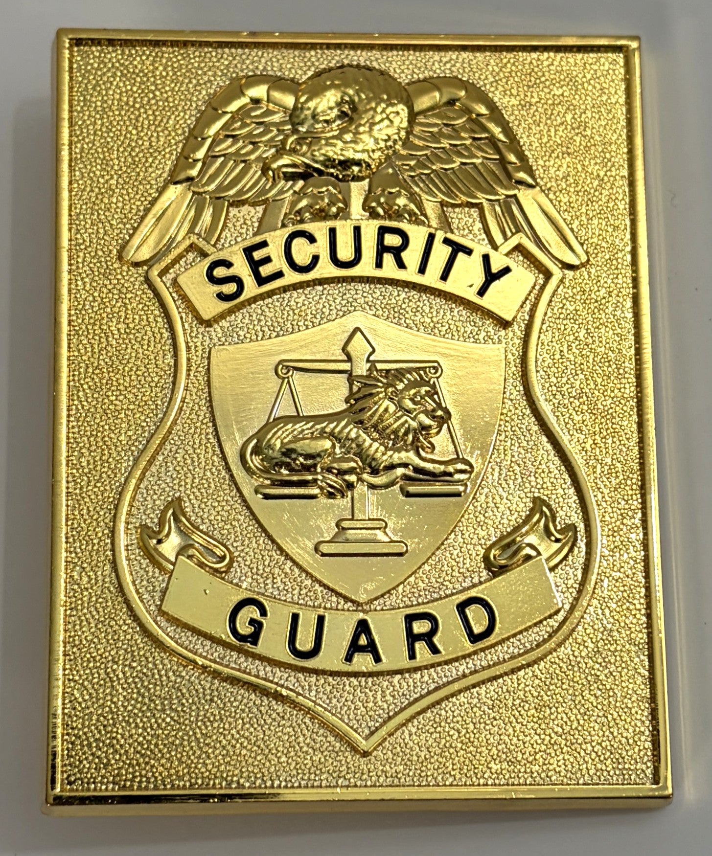 Gold security guard badge with an eagle emblem on a gray background