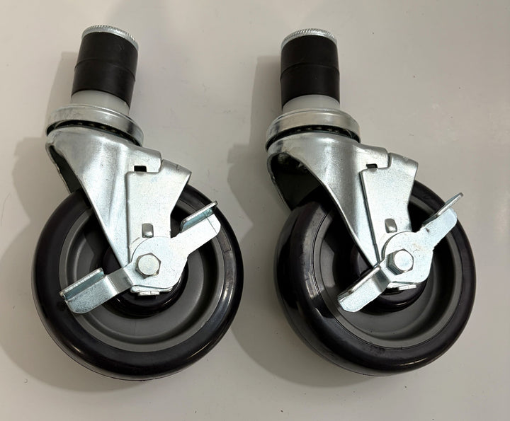 Two black caster wheels with metal brake mechanisms on a light gray background