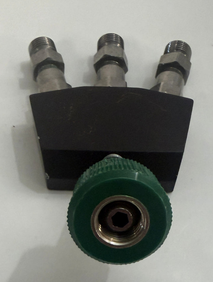 Black metal three-port valve assembly with three threaded fittings and a large green ridged adjustment knob on a white background