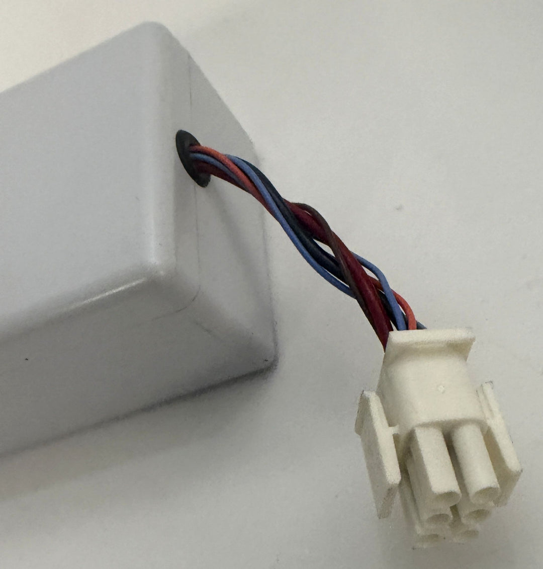 White plastic electrical connector with red, blue, and black wires extending from a white enclosure against a plain background