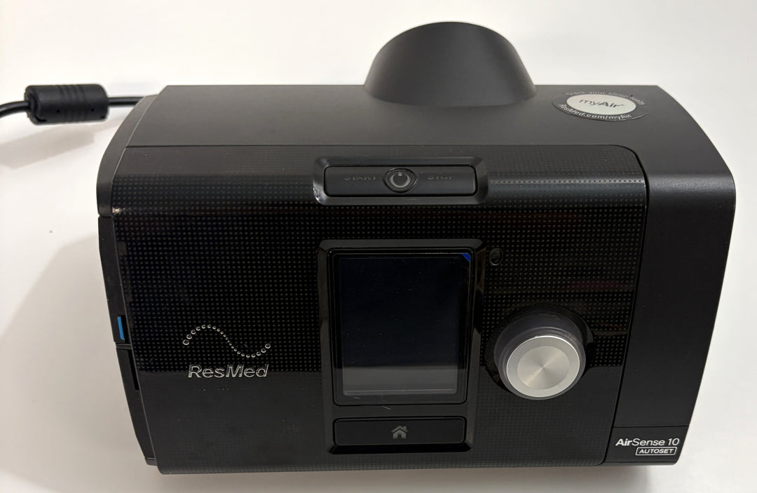 ResMed AirSense 10 AutoSet CPAP console body in black with front display, control dial, and attached power cable