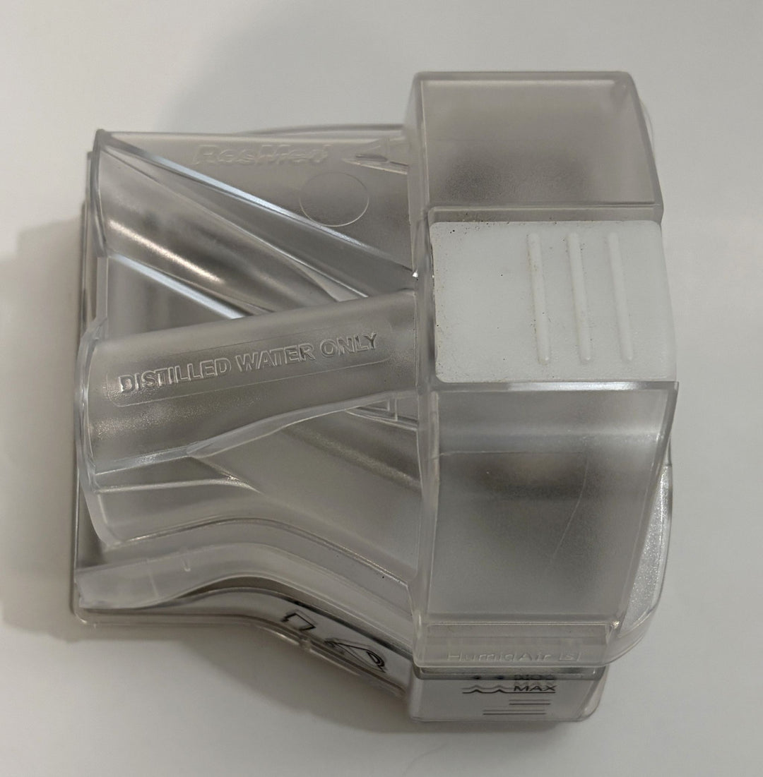 Clear plastic water chamber with molded handle, embossed Distilled Water Only text, and translucent gray lid or housing.