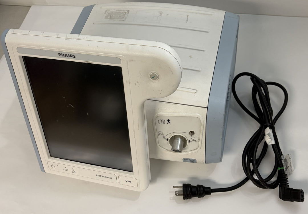 Philips medical patient monitor with blank screen, white housing, control panel, and attached black power cord on a light surface