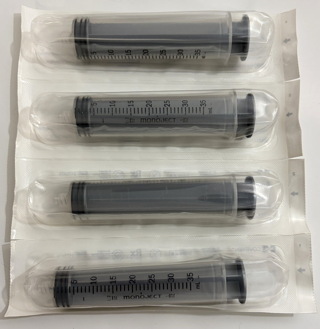 Four individually sealed sterile Covidien Monoject syringes with clear barrels and black plungers, each measuring 35 milliliters, arranged on a white background.