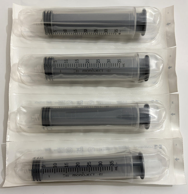 Four individually sealed sterile Covidien Monoject syringes with clear barrels and black plungers, each measuring 35 milliliters, arranged on a white background.