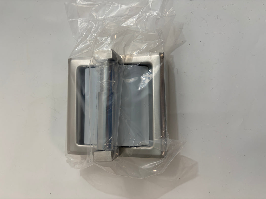 Satin-finished ASI toilet paper holder with protective hood and frame, shown wrapped in clear plastic against a plain light surface.