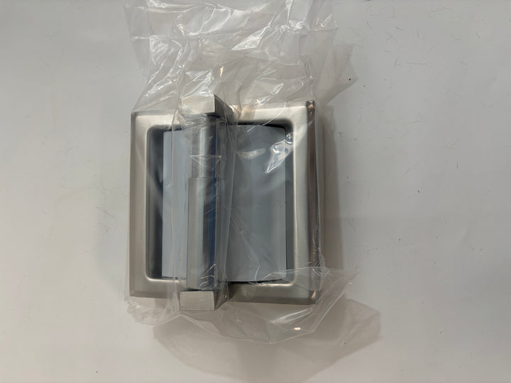 Satin-finished ASI toilet paper holder with protective hood and frame, shown wrapped in clear plastic against a plain light surface.