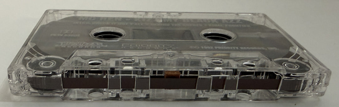 Close-up of a clear plastic audio cassette tape with visible magnetic tape inside, representing a pre-owned music item available from Priority Records.
