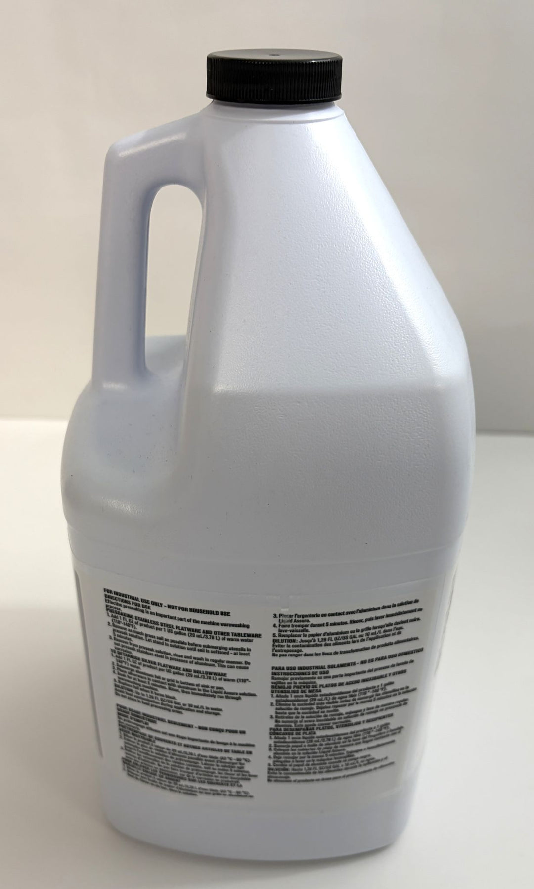 White plastic container with a black screw cap and handle, featuring a multi-language label, containing Ecolab silverware presoaking solution for industrial use.