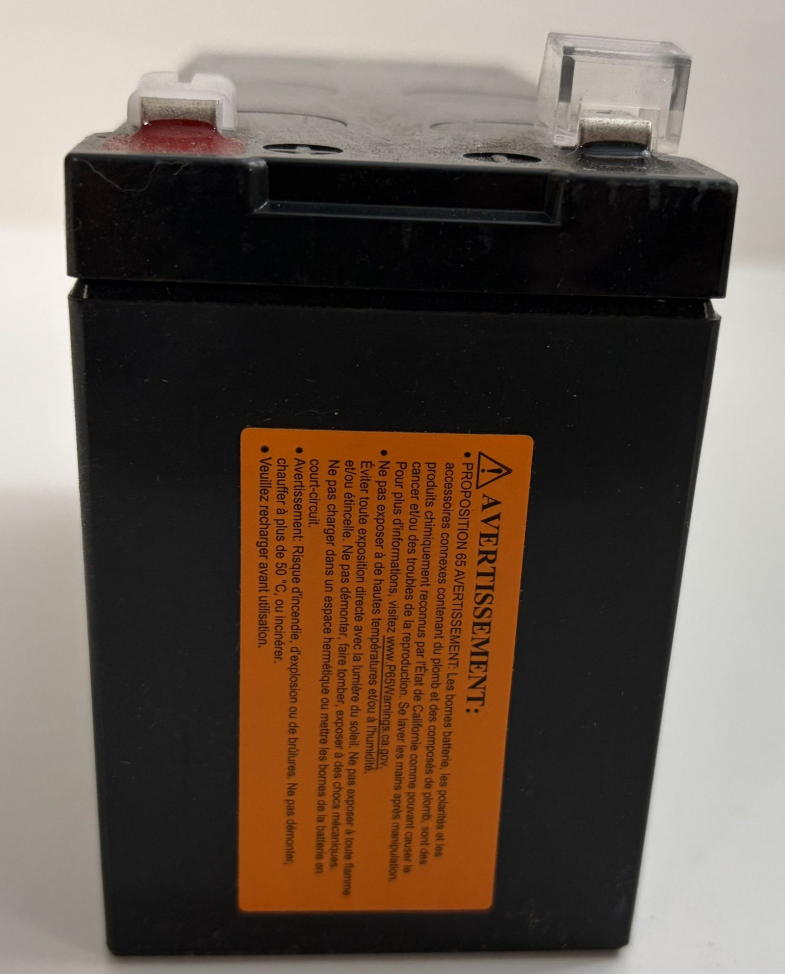 Black battery with an orange warning label on a white background