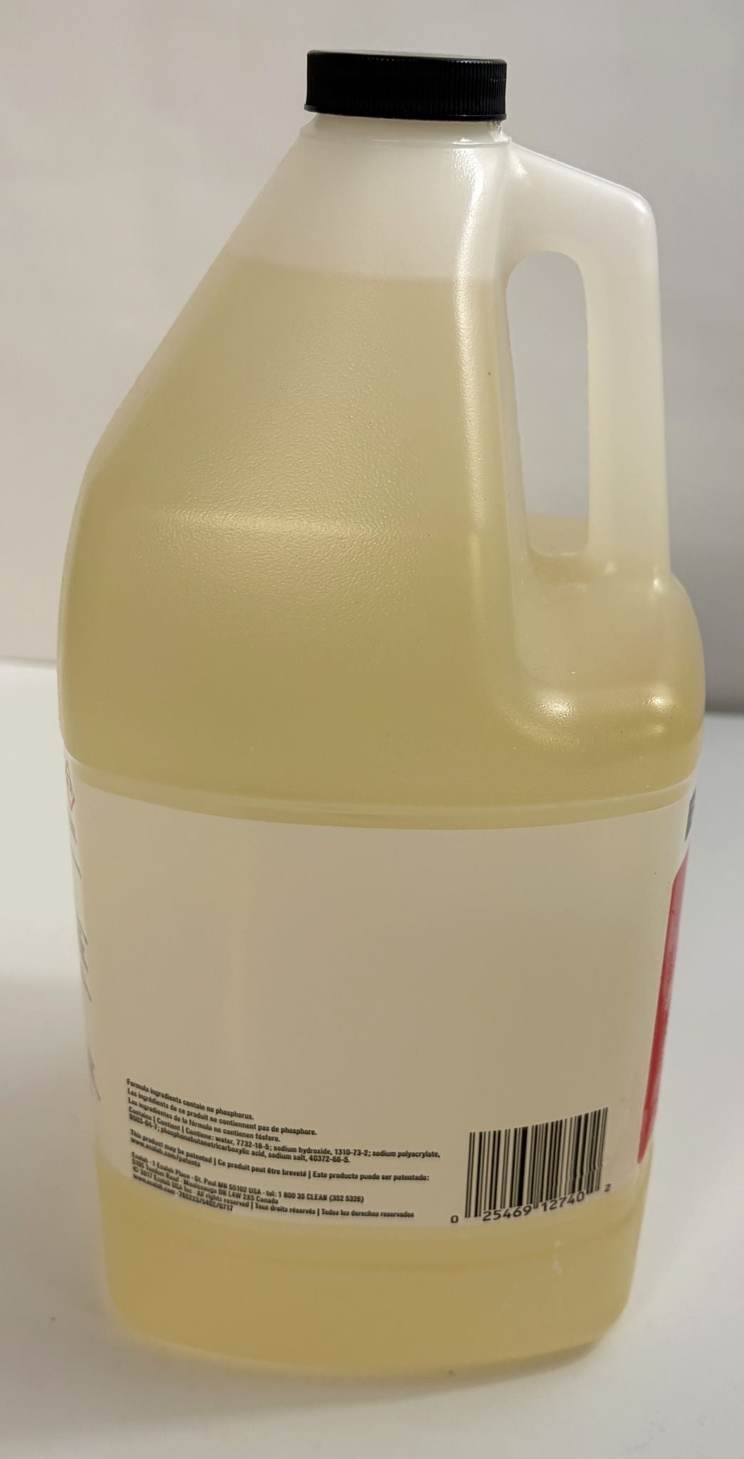 Opaque beige plastic jug with black screw cap half-filled with light yellow liquid, featuring a barcode and small printed text on the back label, representing an industrial cleaner by Ecolab.