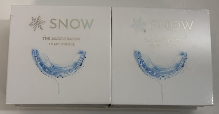 Two Snow branded LED mouthpiece devices for teeth whitening displayed in white retail packaging with blue mouthpiece graphics on a neutral surface.