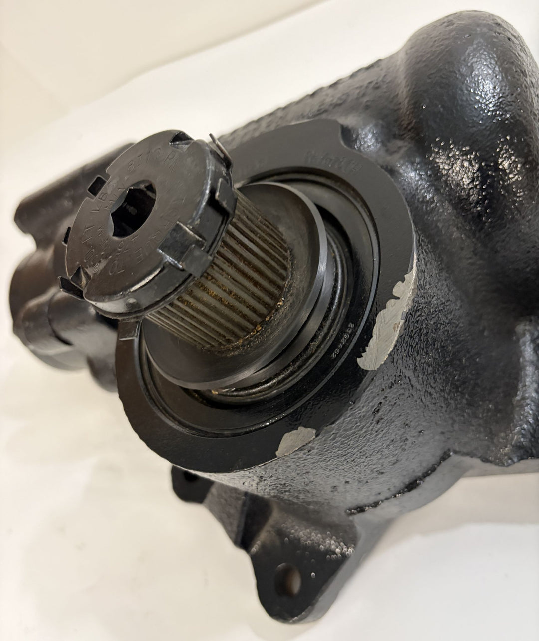 Close-up view of a used Sheppard steering gear component showing a textured black metal housing and splined shaft with a plastic protective cap on a white background.