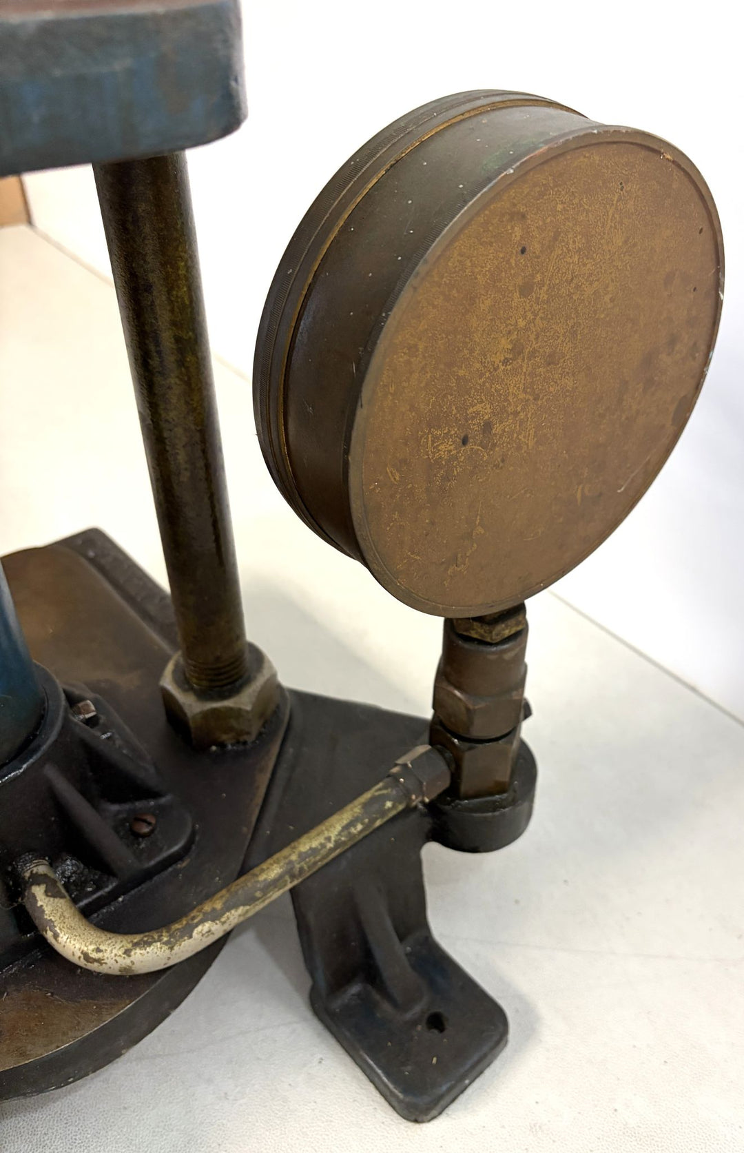 Close-up view of a vintage brass pressure gauge attached to a sturdy metal base, part of a pre-owned hydraulic bench press by Carver Inc.