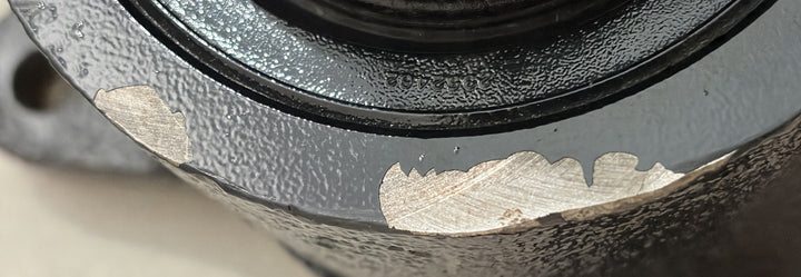 Close-up of a used Sheppard steering gear showing textured black metal housing with visible wear and paint chipping on the surface, suitable for industrial automotive applications.