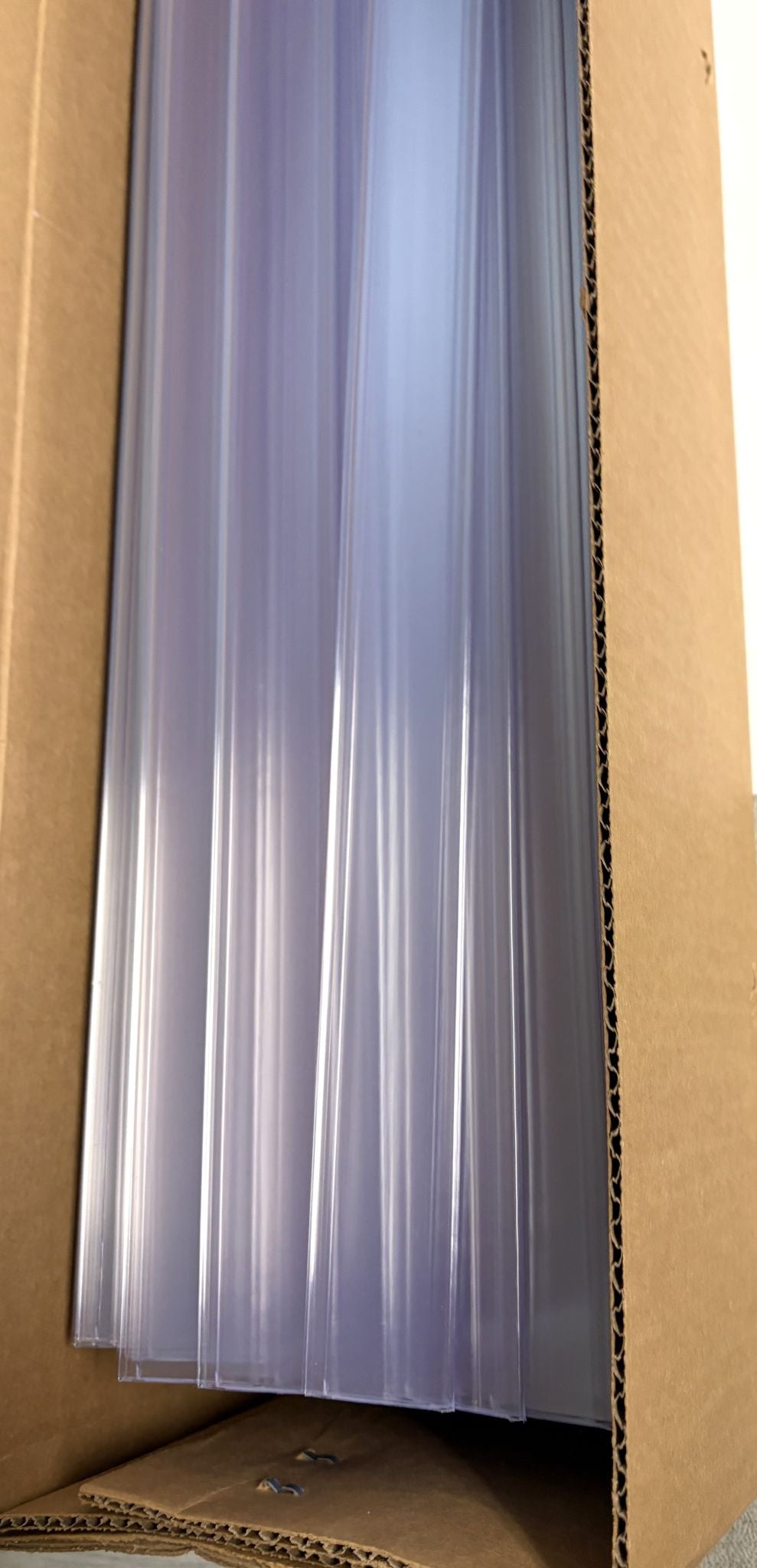 Stack of clear plastic shelf label holders neatly arranged inside a cardboard box, designed for organized product display by Siffron.