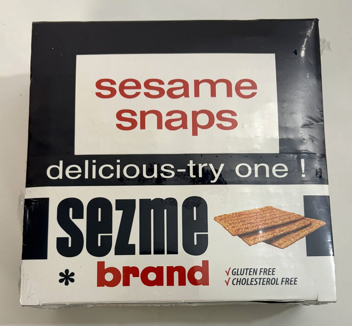 Box of Sezme brand sesame snaps featuring a simple black and white design with red lettering and an image of three crackers, highlighting gluten and cholesterol free snacks.