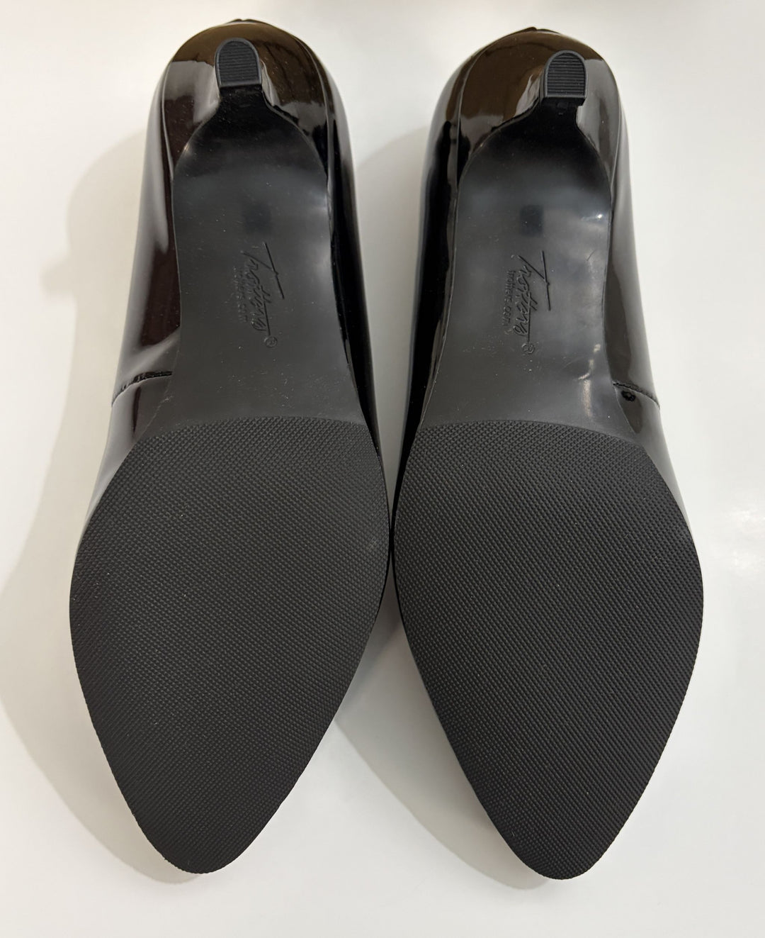 Black patent leather shoes with brand logo on a white background