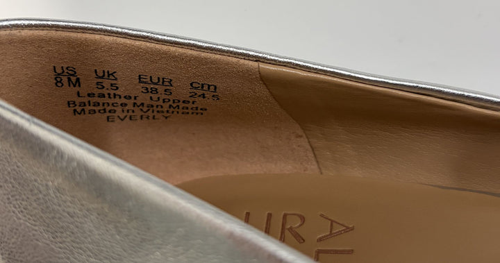Close-up of the inside heel area of a metallic silver shoe showing size markings and material information on the leather upper lining.