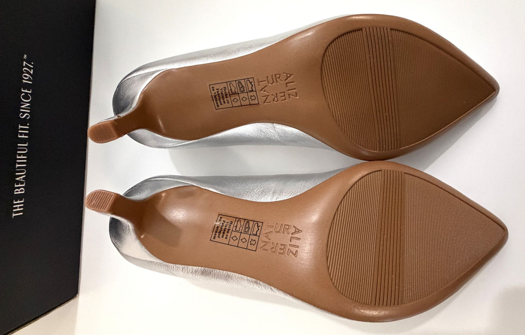 Pair of silver pointed-toe high heels shown from the sole with brown outsoles and textured grip areas.