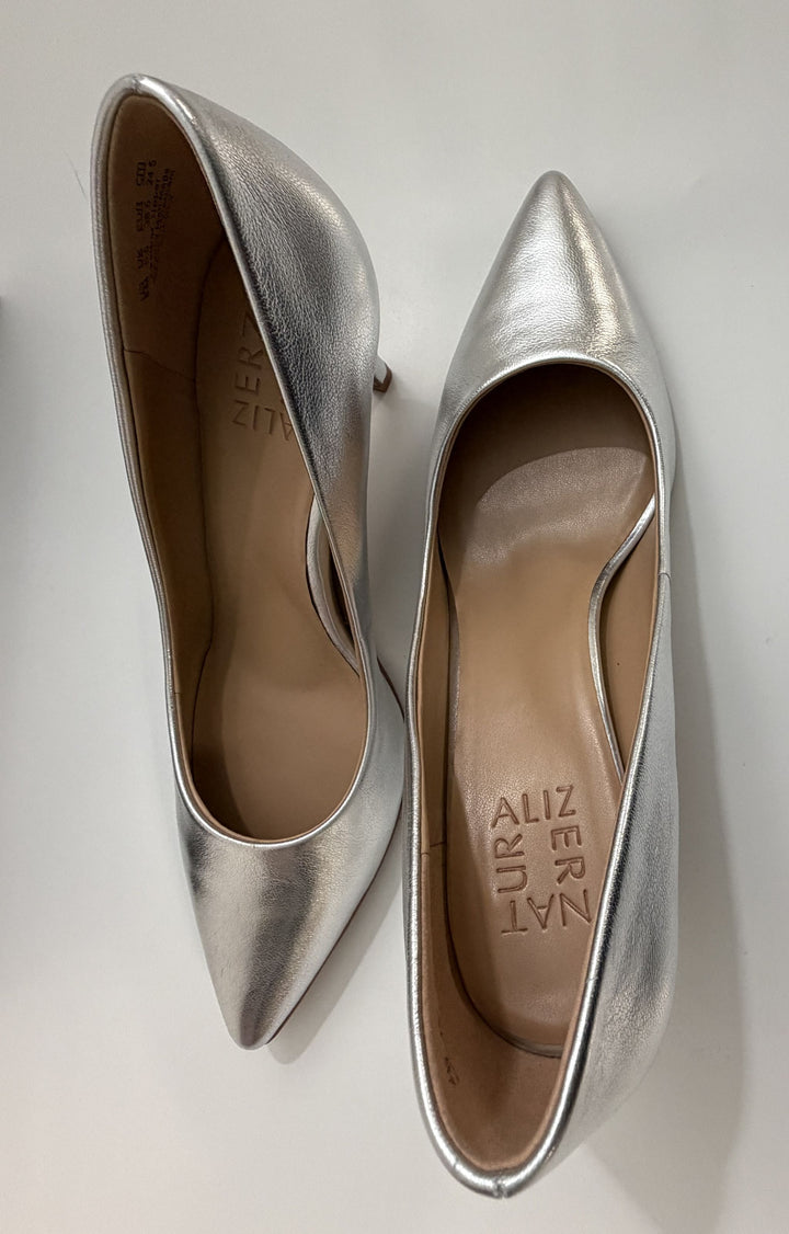 Pair of elegant silver pointed-toe high heels with a smooth leather finish and beige insoles displayed on a white surface.