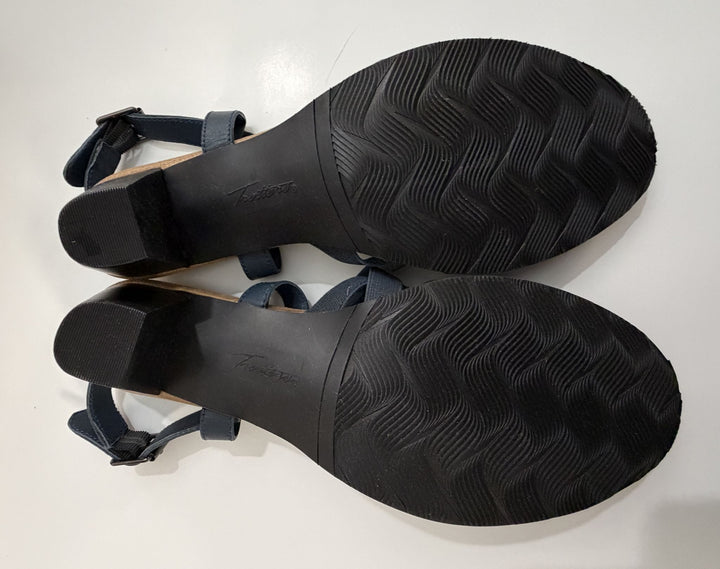 Pair of Trotters navy strappy heeled sandals shown from the rubber soles with textured grip and a low block heel on a white background.