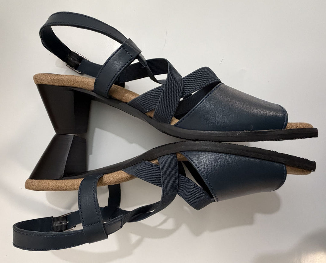 Pair of navy strappy heeled sandals with a wide fit, featuring elastic and leather straps, cushioned tan insoles, and block heels, designed by Trotters.