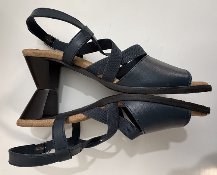 Pair of navy strappy heeled sandals with a wide fit, featuring elastic and leather straps, cushioned tan insoles, and block heels, designed by Trotters.