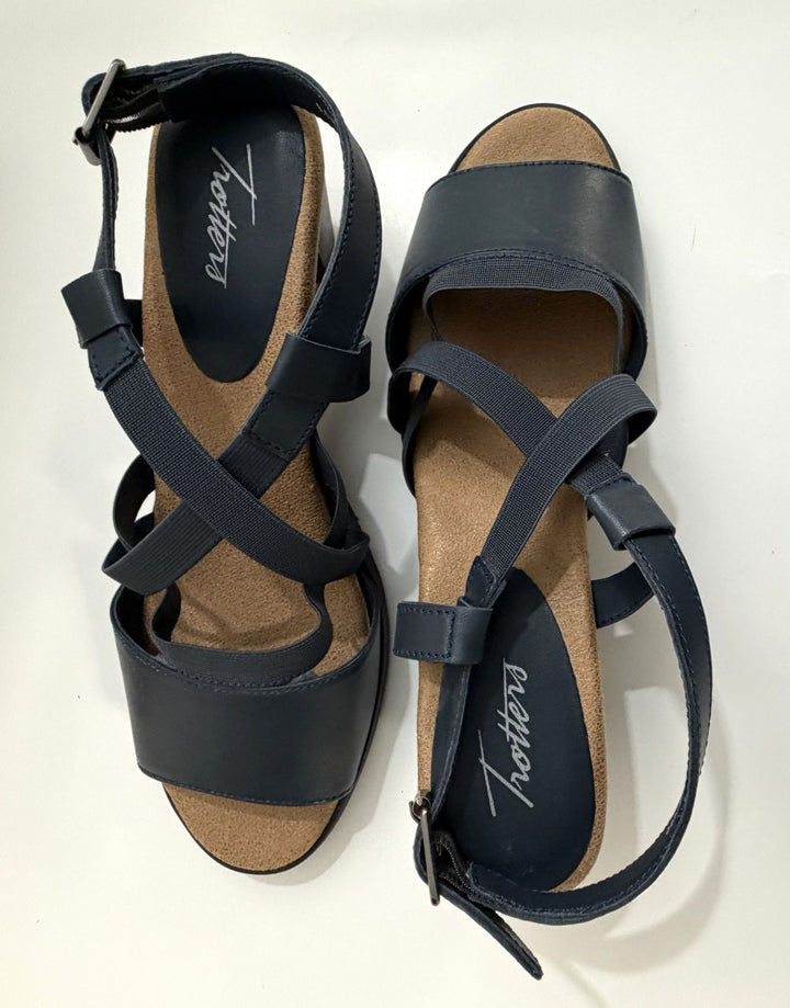 Pair of navy strappy heeled sandals by Trotters with cushioned tan insoles and adjustable ankle straps, displayed on a white background.
