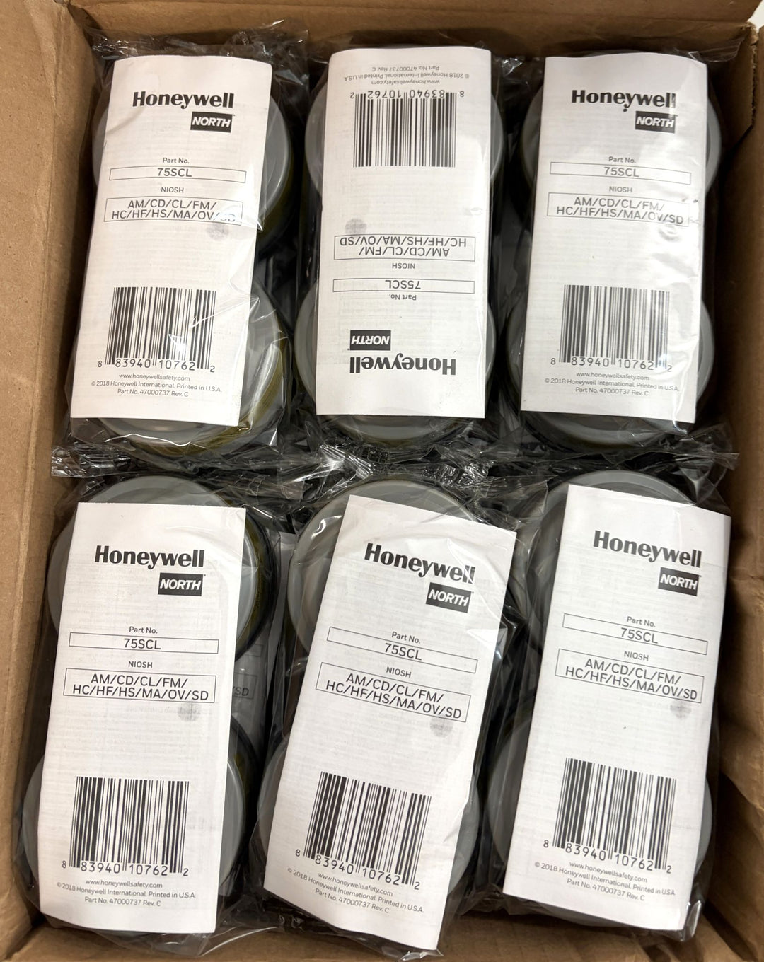 Open cardboard box containing multiple sealed Honeywell North respirator cartridge packs arranged in two rows, featuring white labels with product details and barcodes.