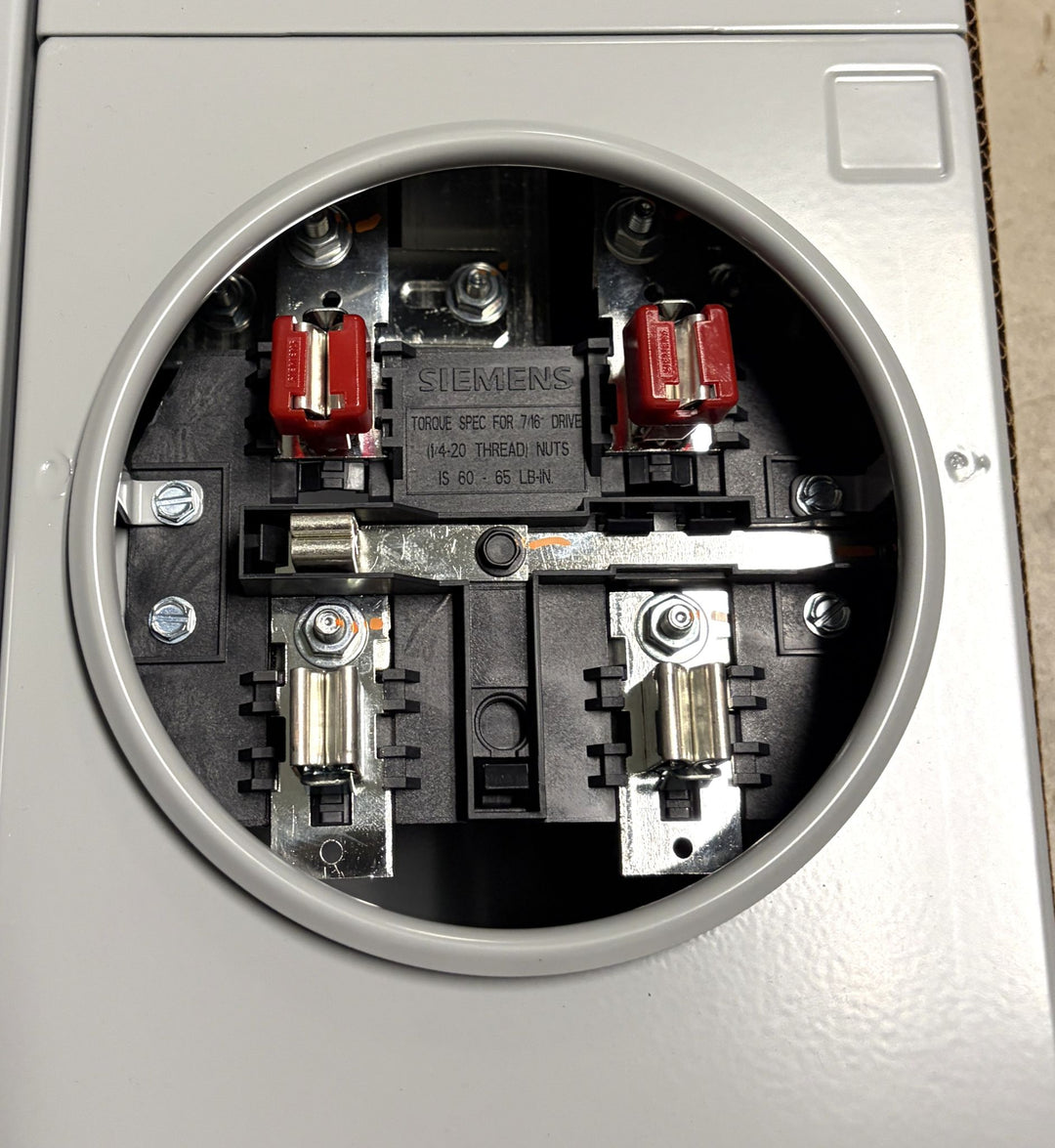 Interior view of a Siemens electrical meter socket with metal contacts, screws, and connection points visible inside a circular gray enclosure, designed for industrial or commercial electrical use.