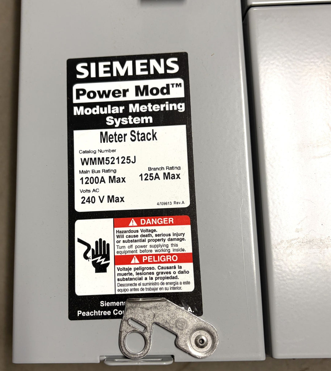 Close-up of a Siemens Power Mod modular metering system label showing electrical specifications, safety warning, and metal locking mechanism on a gray electrical enclosure.