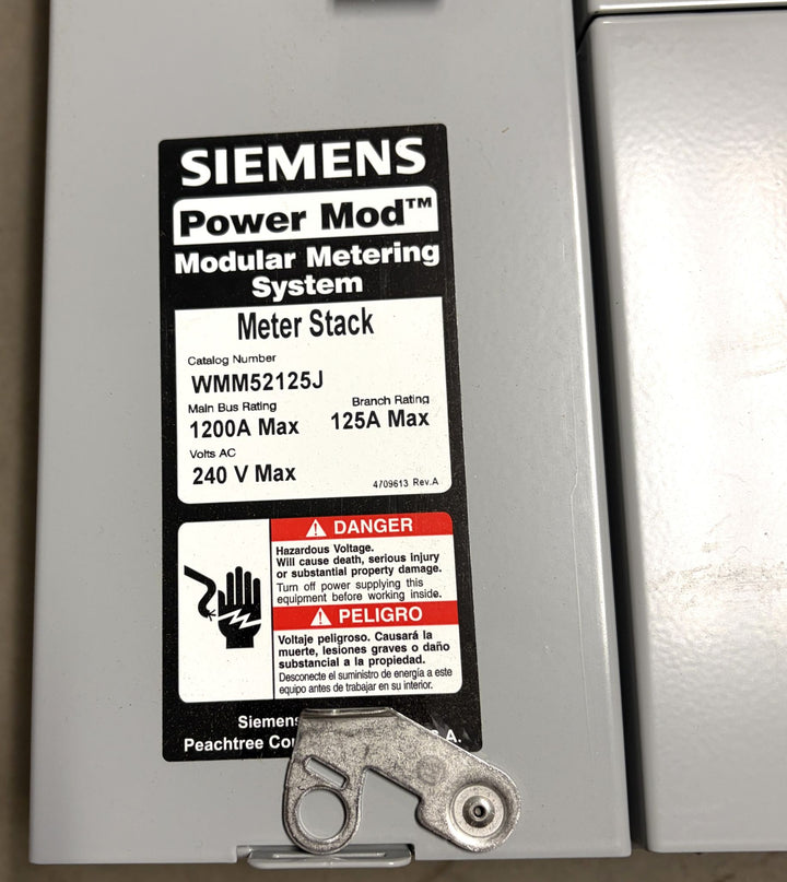 Close-up of a Siemens Power Mod modular metering system label showing electrical specifications, safety warning, and metal locking mechanism on a gray electrical enclosure.