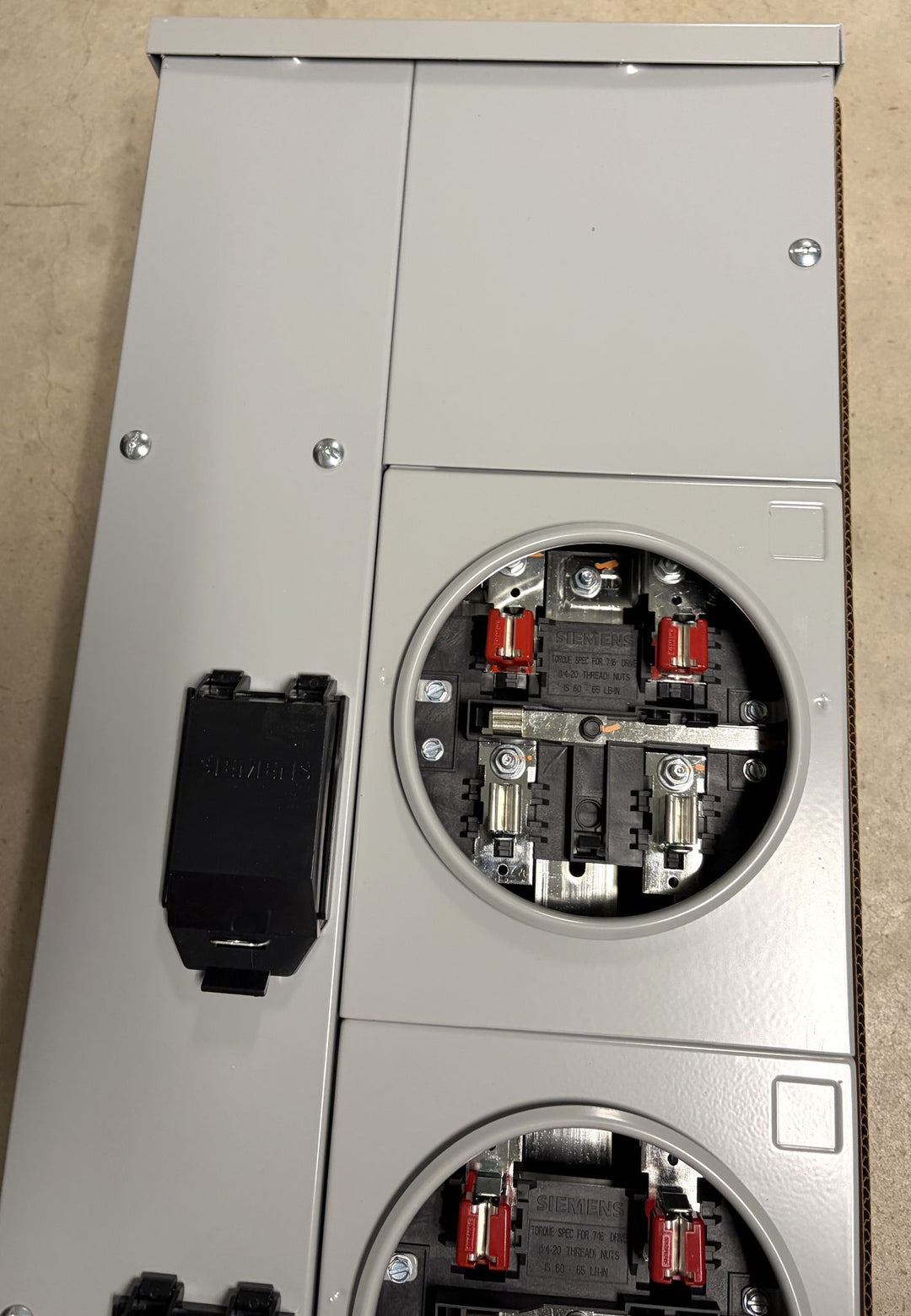 Close-up of a Siemens 3-phase electrical meter socket panel showing fuse holders and internal wiring components in a durable gray metal enclosure for industrial or commercial use.