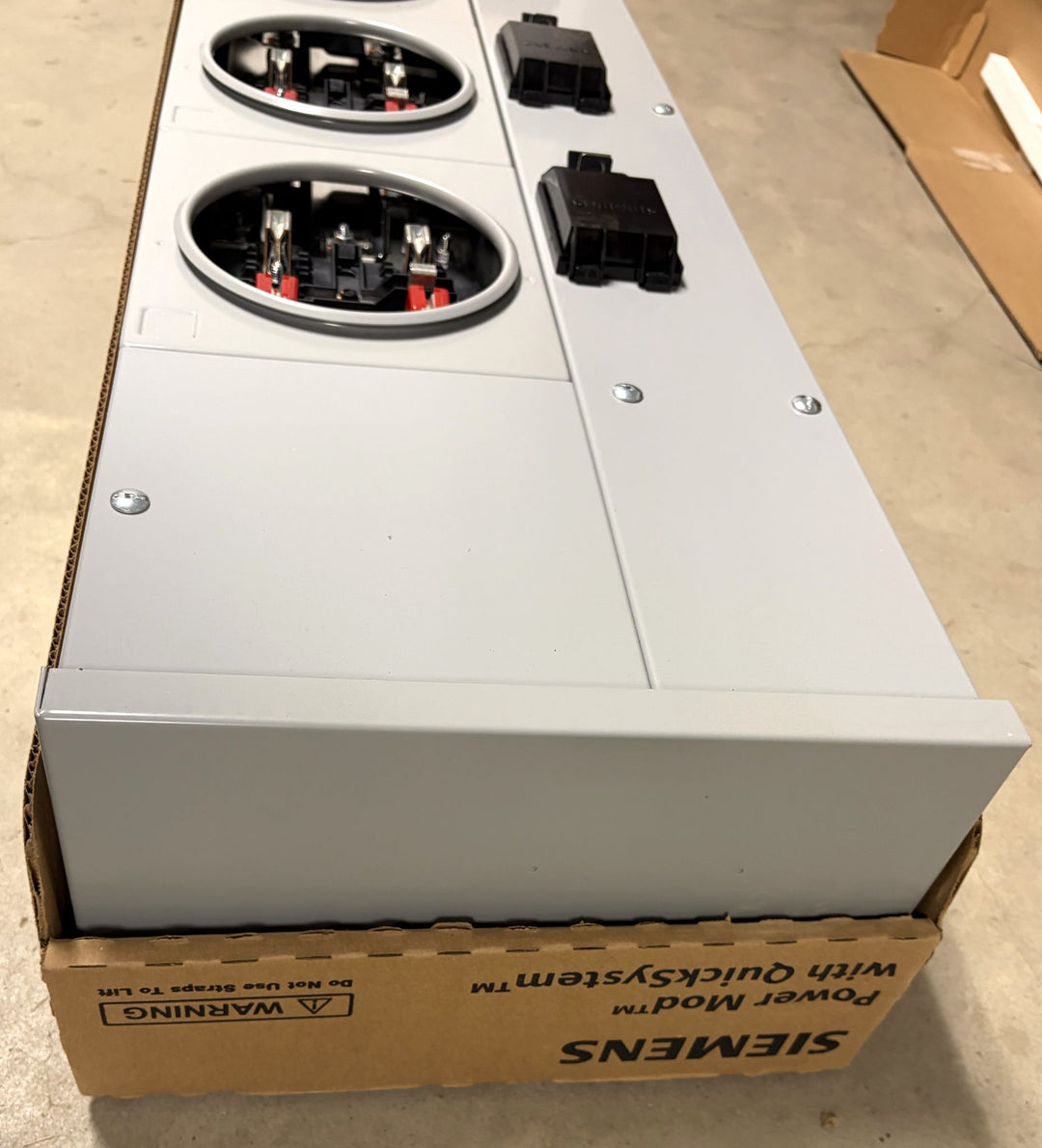Siemens electrical device with multiple circular connector ports and black plastic connectors mounted on a metal panel, shown resting on branded packaging.