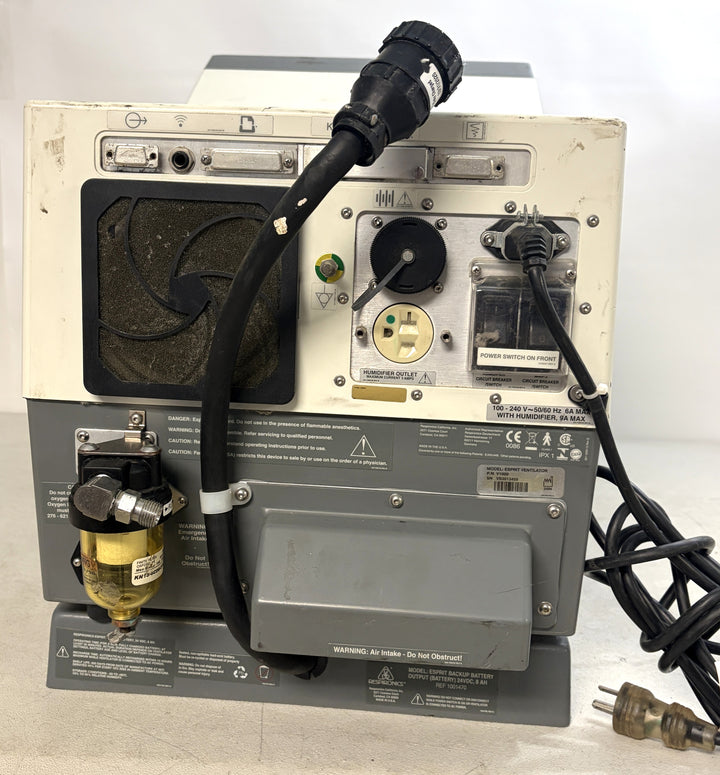Rear view of a used Philips Respironics Esprit V1000 unit showing power cables, ventilation fan, filter, and various ports on a white and gray casing.