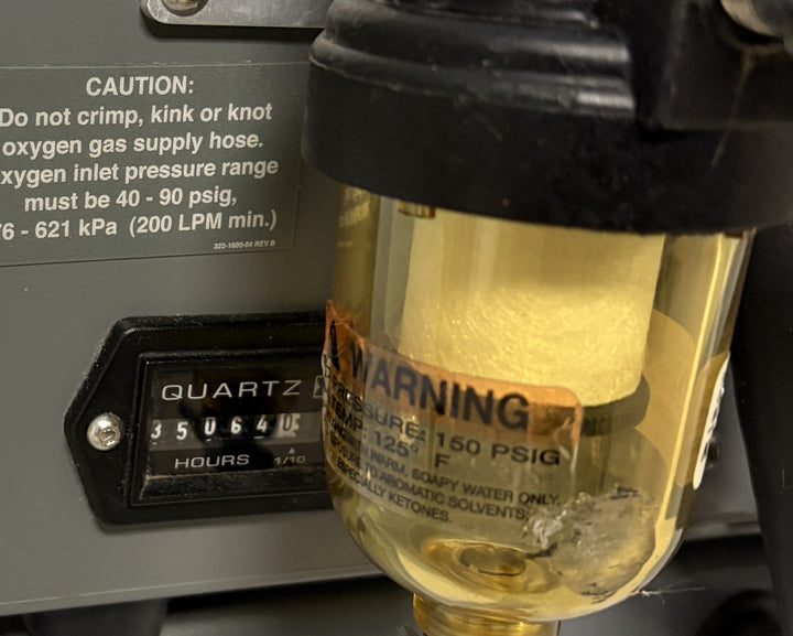 Close-up of a Philips Respironics medical device showing an hour meter reading 350640 hours and a transparent moisture trap with caution and warning labels.