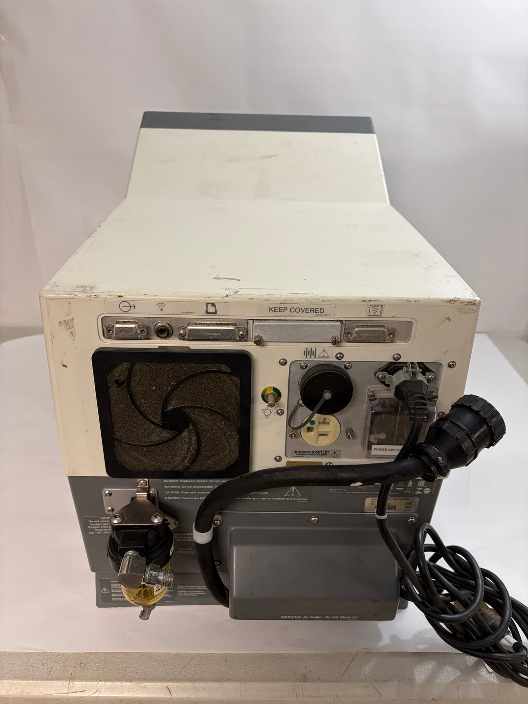 Rear view of a used Philips Respironics device unit for parts or repair showing power cable, ventilation fan, and connection ports on a plain white background.