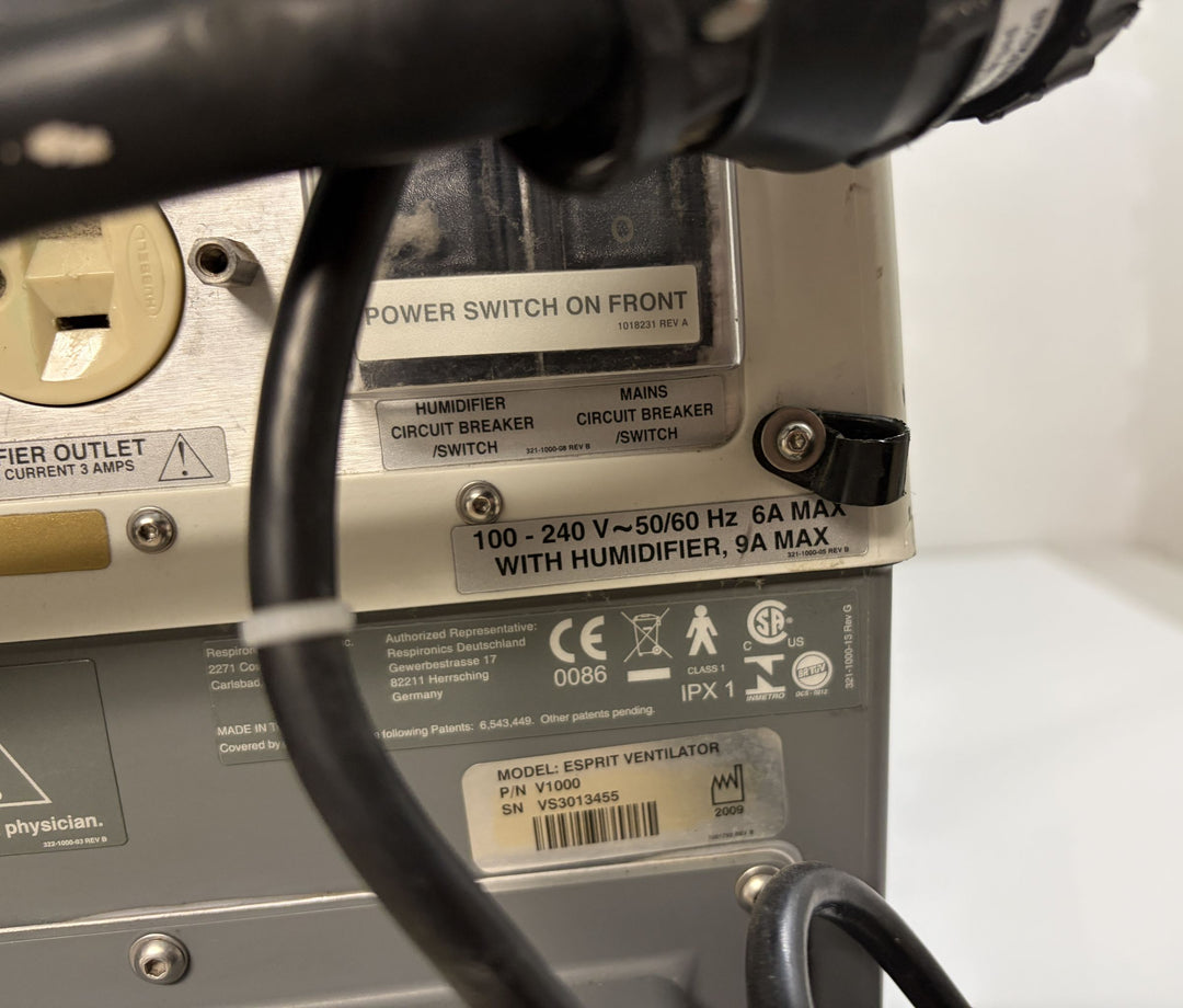 Close-up of the back panel of a Philips Respironics Esprit V1000 ventilator core unit showing electrical specifications, circuit breaker switches, and product identification labels.
