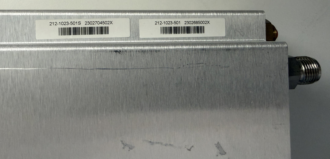 Metallic component with labels and a barcode on a gray background