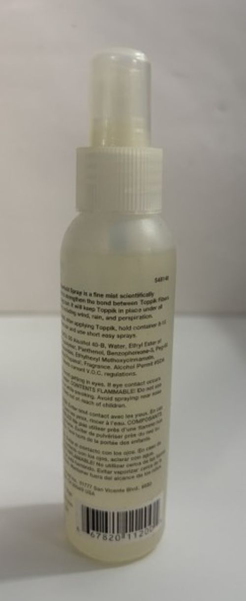 Clear plastic spray bottle of Toppik fiberhold mist with white nozzle and label containing usage instructions and safety warnings on a plain light background.